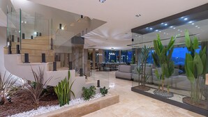 A modern interior with a glass staircase, a seating area with sofas, and a view through large windows. - Villa Buse, wonderful sea view. (Kalkan)