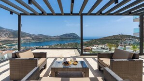 A balcony with wicker furniture, a glass table, and a view of a coastal landscape. - Villa Buse, wonderful sea view. (Kalkan)