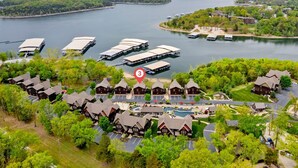 Un resort frente al lago con varias lanchas amarradas, una piscina y cabañas de estilo tradicional.