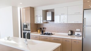 Et moderne køkken med hvide bordplader, rustfrie stålgadgetter og beige skabe.