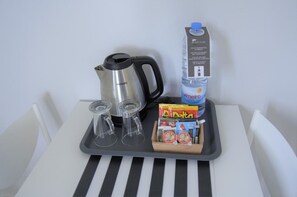 A tray with a Philips coffee maker, two glasses, a water jug, a box of Delta tissues, and a carton of Vimeiro juice. - Apartamentos Turisticos Vitoria By Petit Hotels (Funchal)