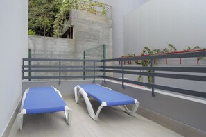A room with two blue beds, a grey railing, and a concrete wall with greenery. - Apartamentos Vitoria By Petit Hotels (Funchal)