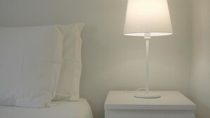 Une table de chevet blanche avec une lampe blanche.