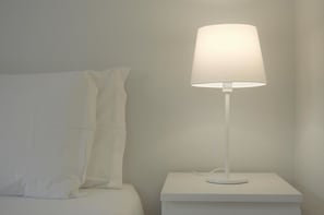 A white bedside table with a white lamp. - Apartamentos Turisticos Vitoria By Petit Hotels (Funchal)