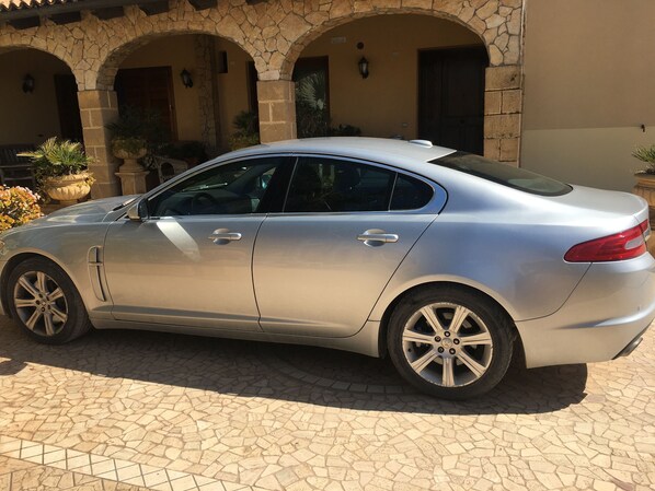 A silver sedan parked in front of a building with stone arches and a tiled patio.