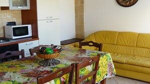 Una cocina compacta con microondas, un lavamanos y un comedor con una mesa dispuesta para dos personas.