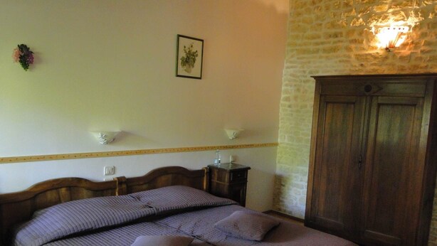 A bedroom with a wooden bed, a nightstand, a wall-mounted light, and a wardrobe.