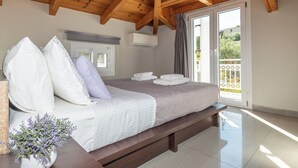 Ein Schlafzimmer mit Holzboden, einem Bett mit weißer und violetter Bettwäsche, einer weißen Klimaanlage und Blick auf einen Balkon mit weißem Geländer.