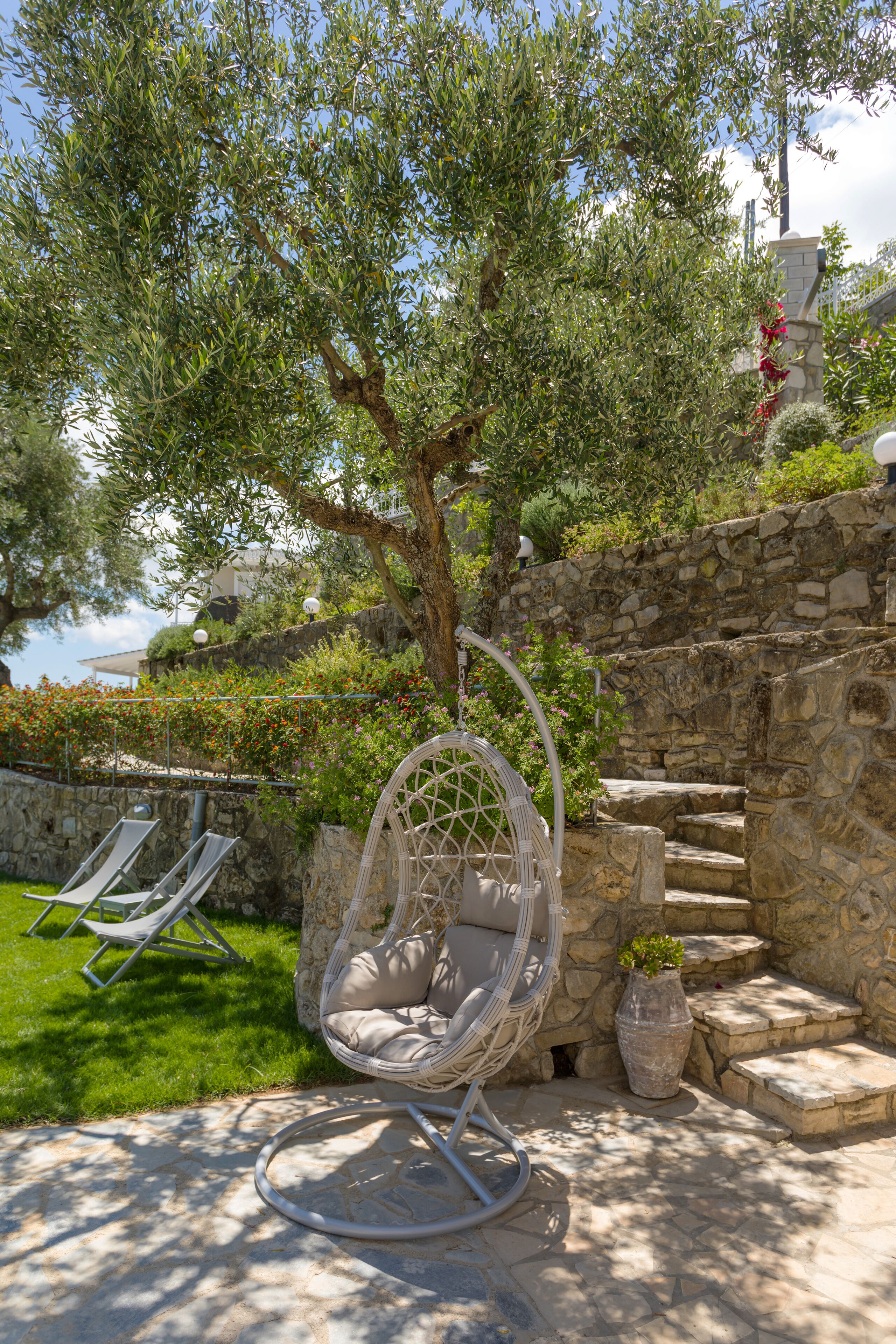 A stone wall with a hanging chair and a potted plant.