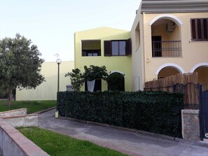 A residential building with a yellow facade, a gated entrance, and a well-maintained hedge. - Villa Veronica Villasimius code IUN P5506 (Villasimius)