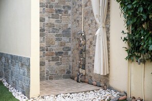 A stone shower enclosure with a tiled floor and a curtain.