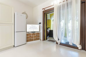 A kitchen with a white refrigerator, a wooden cabinet, and a sign that reads 'VILLA VERONICA VILLASIMIUS'.