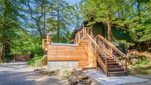 Une cabane en bois avec un escalier menant à une terrasse, entourée d’arbres.
