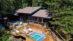 Une terrasse en bois avec une piscine, un espace salon extérieur et une maison dotée d’un toit en pente.