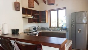Una cocina con armarios de madera, un refrigerador de acero inoxidable, un microondas y una estufa.