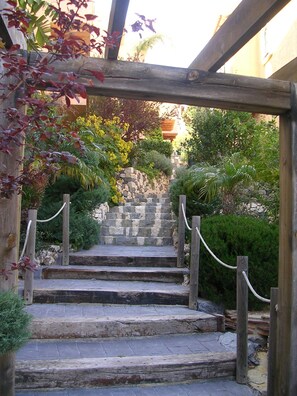 A stone staircase leading up to a wooden pergola, surrounded by lush greenery and a stone wall. - Comfortable villa with sea and mountain view for 5 people. WIFI and garage. (Altea)