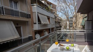 Ein Balkon mit einem Tisch, gedeckt für das Frühstück, inklusive Orangensaftglas, einer Speisenplatte und einer Tasse.