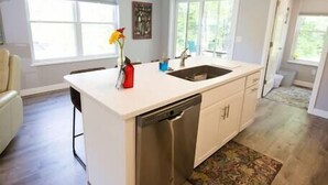Cucina moderna con isola centrale, lavastoviglie in acciaio inossidabile e un'ampia finestra che offre luce naturale.