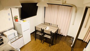 A compact kitchen with a wooden table and chairs, a microwave, a refrigerator, and a sink. - Mifune Central-Bear Shimanouchi No.2 Hotel (Osaka)