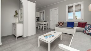 Una sala moderna con un sofá blanco, una mesa de centro y un comedor con sillas y una mesa blancos.