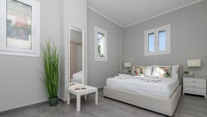Un dormitorio moderno con una cama grande, mesitas de noche, una pequeña mesa con un libro y una planta en maceta.