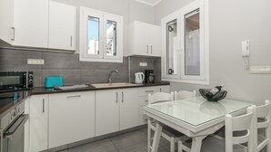 Una cocina moderna con armarios blancos, una mesa de comedor con superficie de vidrio y una cafetera.