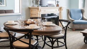 Un coin repas avec une table ronde dressée pour quatre personnes, entourée de chaises en bois foncé dotées d’assises rembourrées.