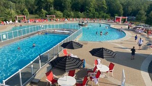 Un espace piscine comprenant plusieurs bassins, des chaises longues et des parasols.