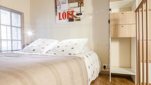 Een slaapkamer met een bed, een houten garderobe en een poster aan de muur.