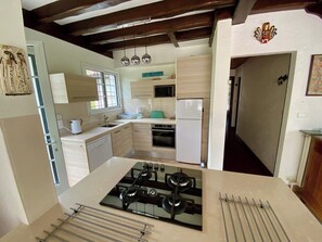 A kitchen with a gas stove, a microwave, and a refrigerator. There is a window providing natural light. - Cottage with an idyllic garden at the lake G0239 (Lacanau)