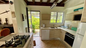 A modern kitchen with a gas stove, white cabinets, a dishwasher, and a window providing natural light. - Renovated landaise style house with enchanted garden, 2 steps from the lake (Lacanau)