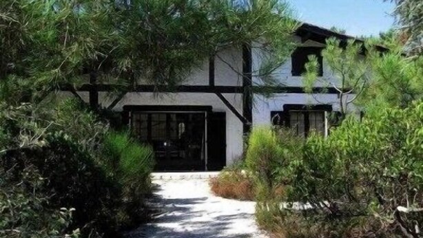 A traditional building with a black and white exterior, surrounded by dense greenery. - Renovated landaise style house with enchanted garden, 2 steps from the lake (Lacanau)