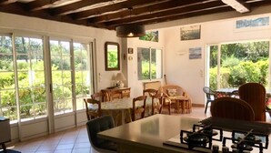 A spacious kitchen with a large island, ample natural light from large windows, and a view of greenery outside. - Renovated landaise style house with enchanted garden, 2 steps from the lake (Lacanau)