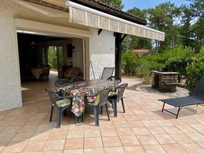 An outdoor patio with a table and chairs, a barbecue grill, and a covered area.