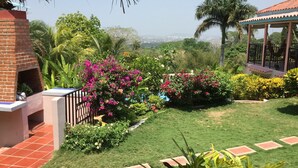 Ein Garten mit einer Ziegelstruktur, einem Gazebo und Blick auf die Stadt.