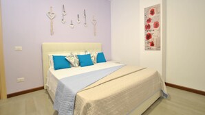 Ein Schlafzimmer mit Bett, Kissen, einem Wandbild und einem Lichtschalter.