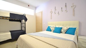 Ein Schlafzimmer mit Etagenbetten, einem großen Bett mit blauen und gemusterten Kissen sowie herzförmigen Wanddekorationen.