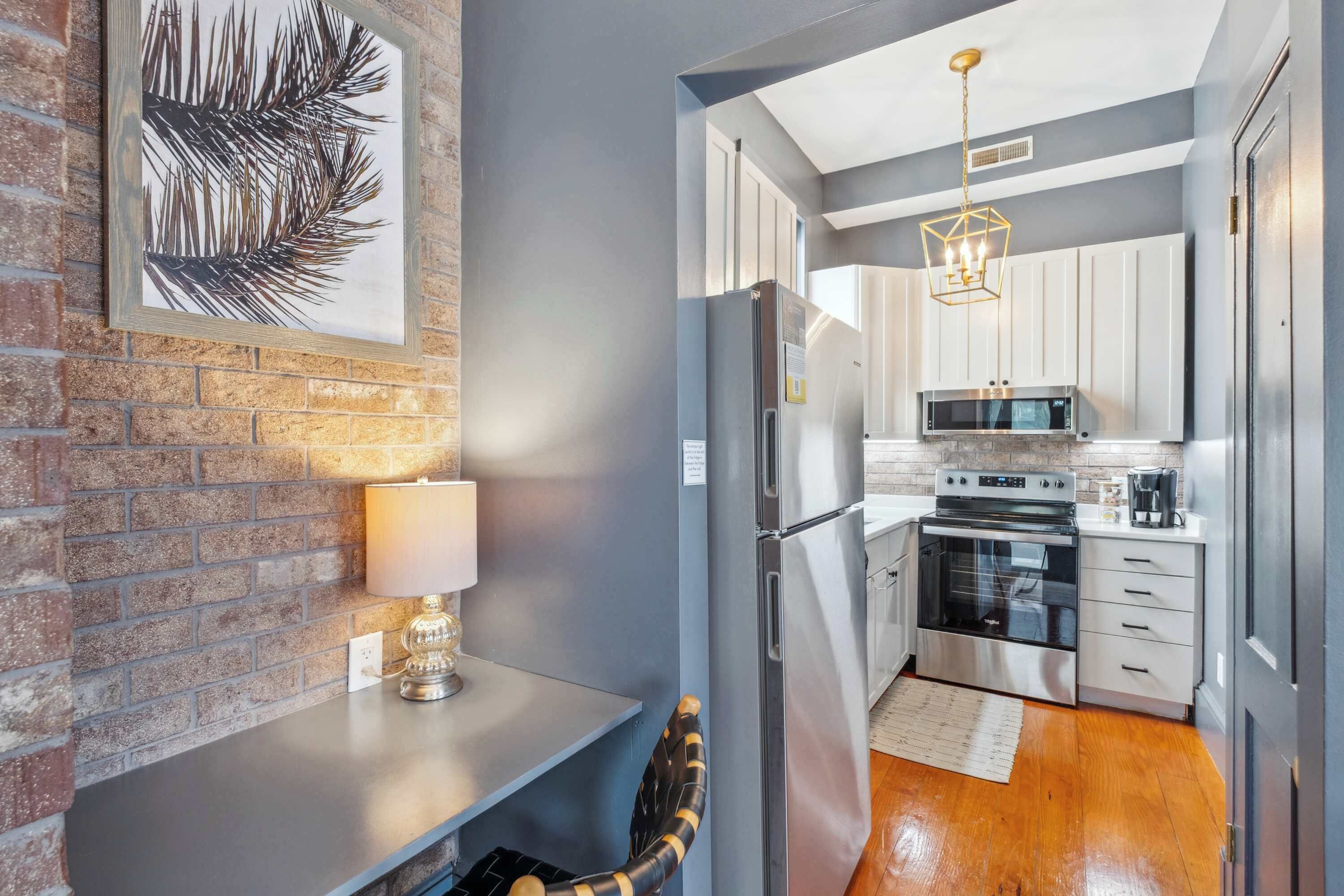 A modern kitchen with a refrigerator, microwave, oven, and a dining area with a table and chair.