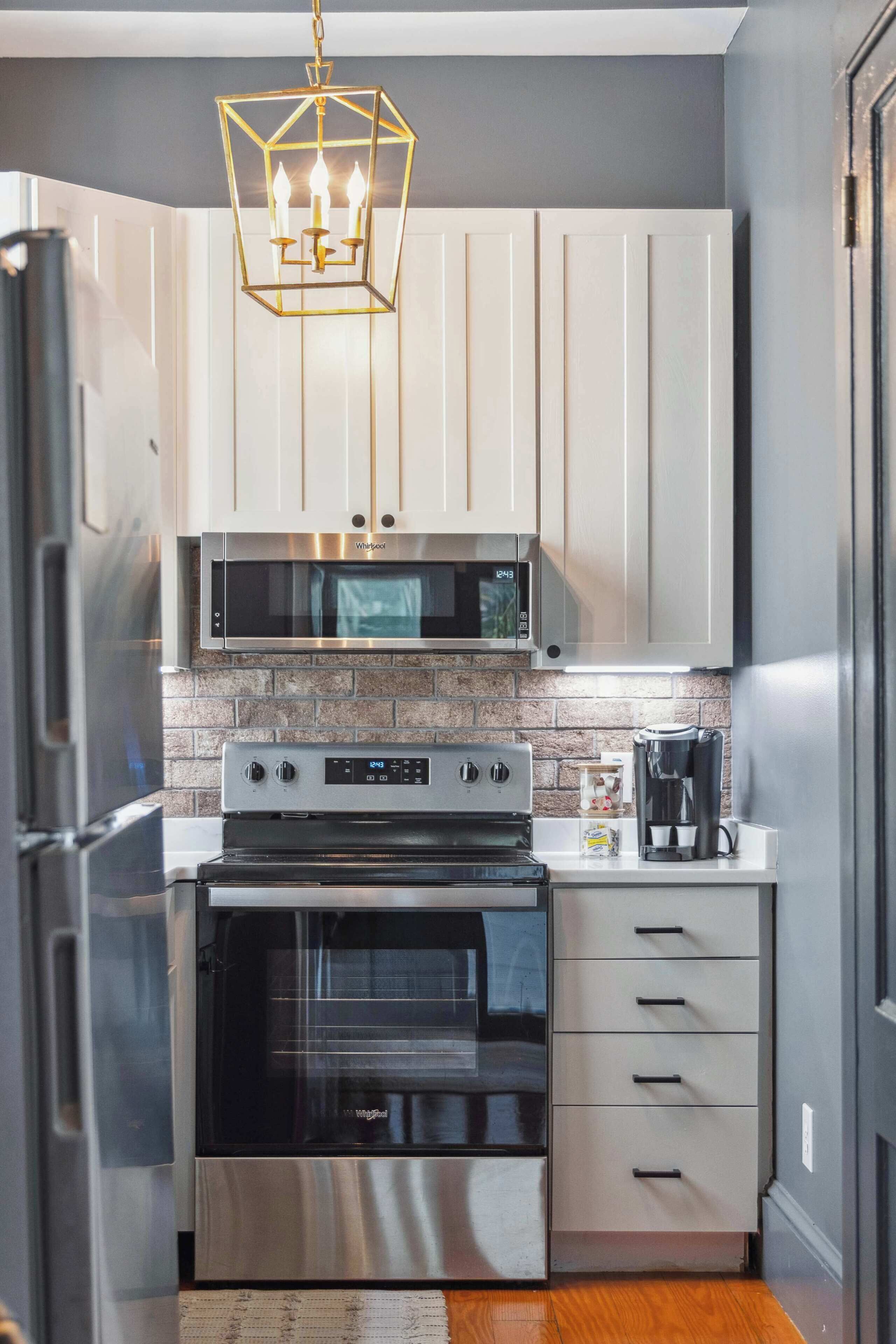 Una cocina moderna con electrodomésticos de acero inoxidable, microondas, horno y cafetera.