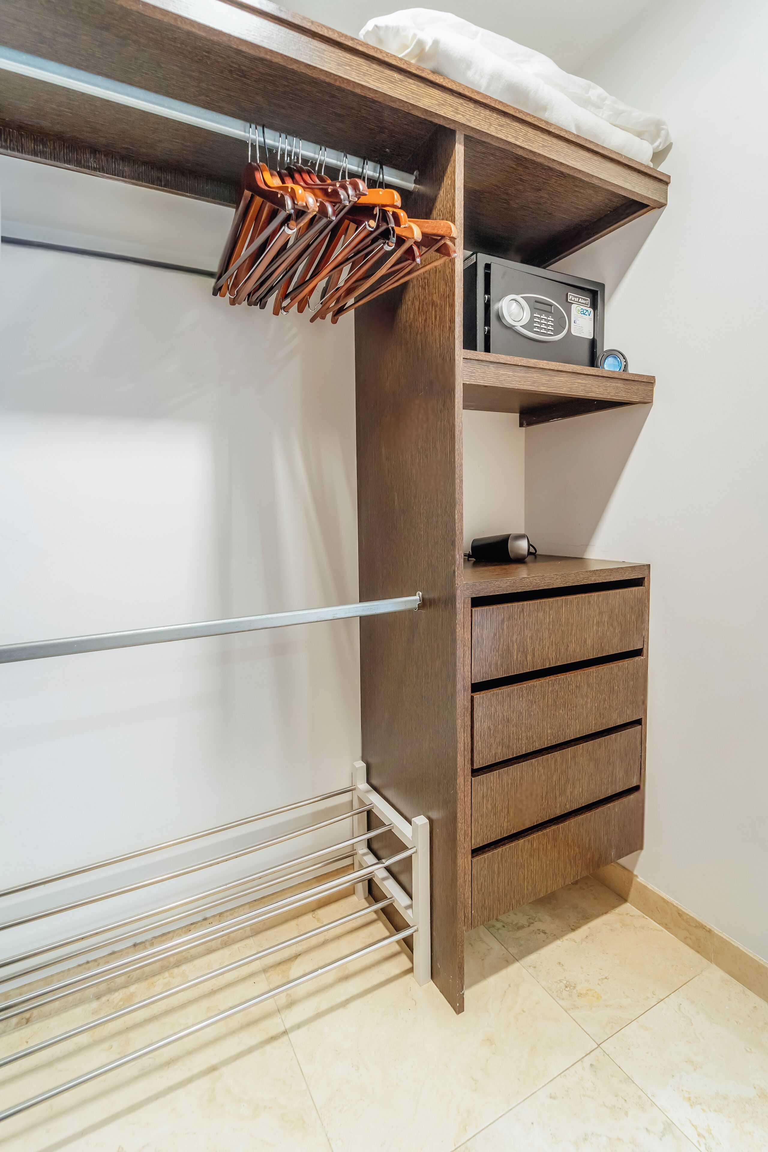 Un dressing avec une armoire en bois, une tringle à vêtements et une petite étagère sur laquelle se trouve une radio.