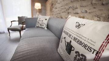 Ein modernes Wohnzimmer mit einem grauen Sofa, einem dekorativen Kissen mit Text, einer Lampe und einem Sessel.