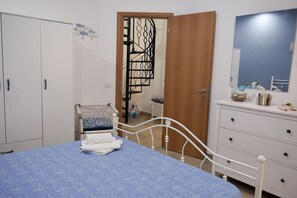 Une chambre à coucher comprenant un lit, une armoire, une commode, un miroir et un escalier en colimaçon.
