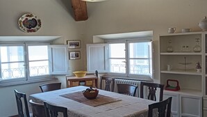 A dining area with a wooden ceiling, a table set with chairs, and a window with a view. - Talents Home Historical center (Lucca)