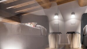 A modern bedroom with a sloped ceiling, built-in headboard, bedside lamps, and a large mirror. - "GIADA" - Elegant Penthouse for 4 people on the 3rd floor on 2 levels (Firenze)