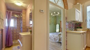 A compact bedroom with a bed, a bathroom with a shower, and a kitchenette. - Central apartment for visiting Florence (Firenze)