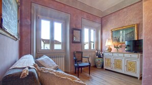 A cozy living room with a sofa, a chair, a cabinet, and a television. - Central apartment for visiting Florence (Firenze)