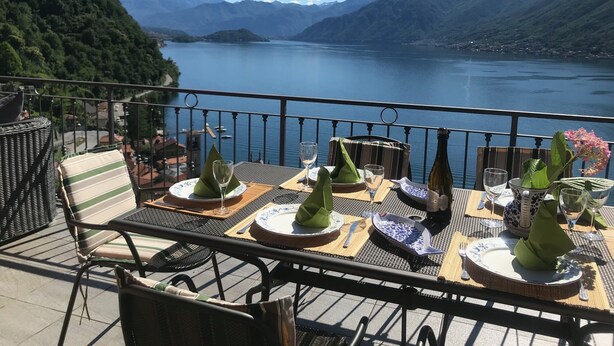 Une table dressée pour le dîner, avec vue sur un lac et des montagnes.