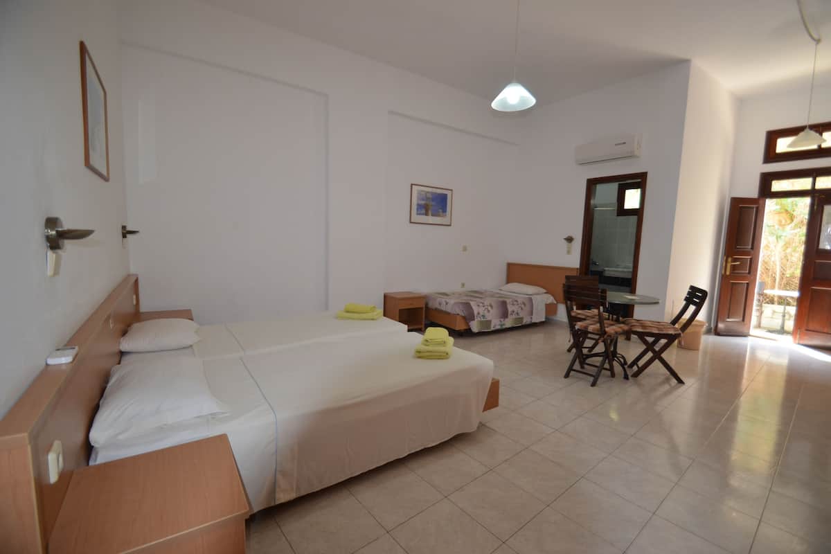 A hotel room with a large bed, a desk, a chair, and a small table. There is a window with a view of the outside.