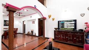 A spacious living area with a modern design, featuring a large flat-screen TV, a dining table, and a decorative vase. - Villa Calangute Phase 4, Near Calangute Beach & Restaurants (Calangute)