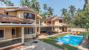 A two-story house with a swimming pool, outdoor furniture, and palm trees in the background. - Villa Calangute Phase 4, Near Calangute Beach & Restaurants (Calangute)